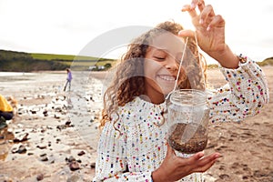 Family Looking In Rockpools On Winter Beach Vacation