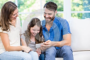 Family looking at smart phone while sitting on sofa