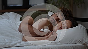 Family love and connection. Young loving middle eastern man and woman sleeping in bed, cuddling together, tracking shot