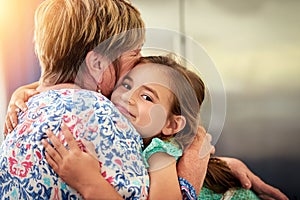 Family love. Portrait of an adorable little girl hugging her grandmother at home.