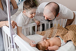 Family love to newborn infant in crib