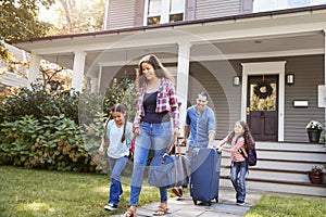 Family With Luggage Leaving House For Vacation photo