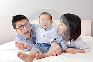 Family lying on bed with funny facial expression