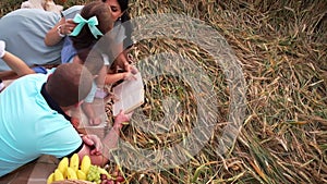 Family is lying on a blanket in a wheat field and reading a book together in slowmo