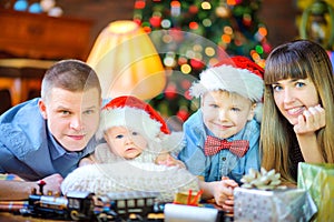 Family is lying on the floor against the backdrop of a festive Christmas tree