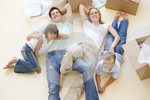 Family lying on floor by open boxes in new home