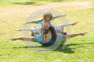 Family lying on grass in park. Parents giving child piggybacks in countryside.