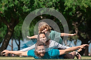Family lying on grass in park. Parents giving child piggybacks in countryside. Fly concept, little boy is sitting