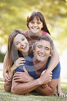 Family Lying On Grass In Summer Park