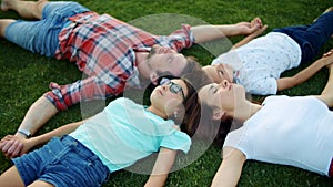 Family lying on green grass in circle. Cute kids and parents relaxing in field