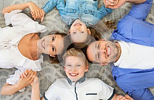 Family Lying Holding Hands Smiling Posing On Floor Indoors, Above-View