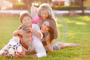 Family Lying In Pile Up On Grass Together