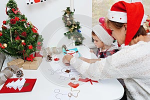 Family making seasonal greeting cards together at christmas time, grandmother with granddaughter at home