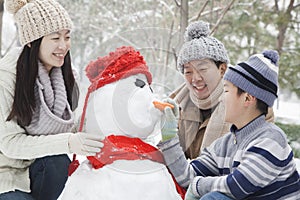 Family making snowman in a park in winter