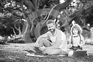 Family man business online. Father and son working on laptop remote in the park.