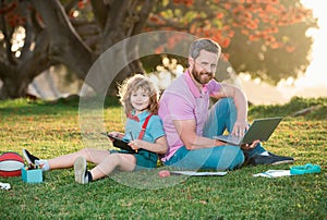 Family man business online. Father and son working on laptop remote in the park.