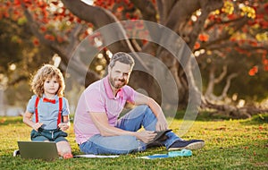 Family man business online. Father and son working on laptop remote in the park.