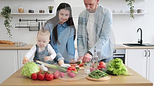Family man and wife feeding daughter with red vegetable