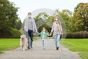 Family in masks with labrador dog in park