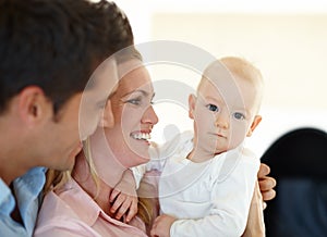 Family means being loved no matter what. a contented family smiling while holding their baby.