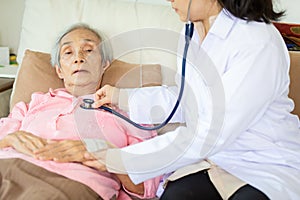 .Family medical female doctor or nurse checking senior patient using stethoscope in hospital bed or home,young asian caregiver