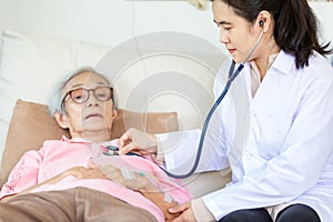 Family medical female doctor or nurse checking senior patient using stethoscope in hospital bed or home,young asian caregiver