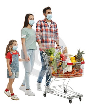 Family in medical masks with shopping cart full of groceries on white background