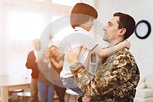 Young son meets a man in camouflage at home.