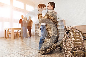 Young son meets a man in camouflage at home.