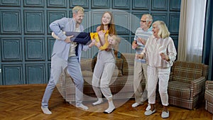 Family members of different generations having fun listening music, dancing crazy in room at home