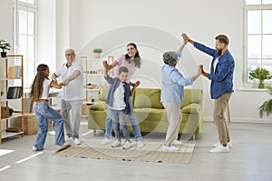 Family members of different generations having fun listening music and dancing in room at home.