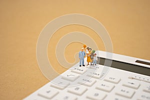 Family Miniature people Pay queue Annual income TAX for the year on calculator. using as background business concept and finance