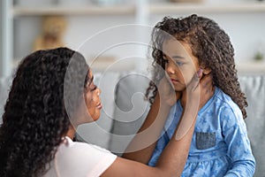 Family misunderstanding, childhood problems. Young black mother comforting her sad offended daughter at home