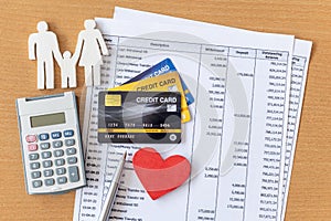 Family model and calculator on Bank statement and credit card on a Wooden table