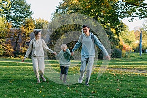 a family mom and 2 sons are having fun, running in the park and jumping. Sons, children, mom, run, play, rejoice, enjoy