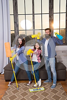 Family mom dad and daughter with cleaning supplies at living room. We love cleanliness and tidiness. Cleaning together