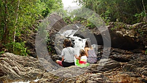 Family mom dad daughter sit and enjoy waterfall view