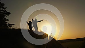 Family mom and daughter travel vacation. Woman with raised hands on top of a mountain looking at sunset. Hiker Girl