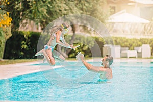 Family of mom and little daughter enjoying summer vacation in luxury swimming pool