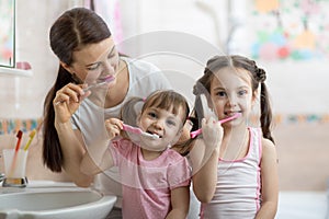 Family mom and two little girls brush their teeth