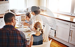 Family, morning and breakfast by table in kitchen for meal, eating or bonding time together at home. Mother, father and