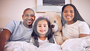 Family, morning and happy portrait on a bed at home with a smile, teddy bear and comfort for quality time. Man, woman or