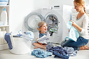 Family mother and child girl in laundry room near washing machi