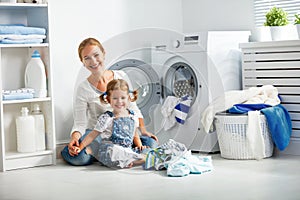 Family mother and child girl in laundry room near washing machi