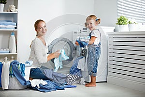 Family mother and child girl in laundry room near washing machi