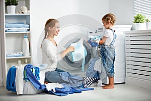 Family mother and child girl in laundry room near washing machi