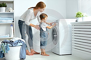 family mother and child little helper in laundry room near washing machine