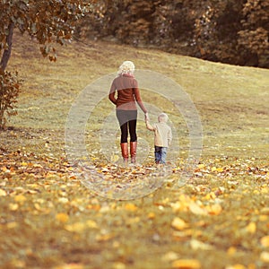 Family mother and child walking together in autumn park