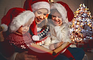 Family mother and children read a book at christmas near firep