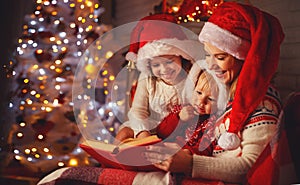 Family mother and children read a book at christmas near firep